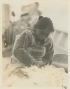 Image of Eskimo [Inughuit] woman  sewing skins  [scraping skins with an ulu]